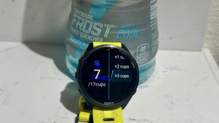 The Garmin Forerunner 965 shows off a hydration tracking data app, sitting in front of a Gatorade bottle.