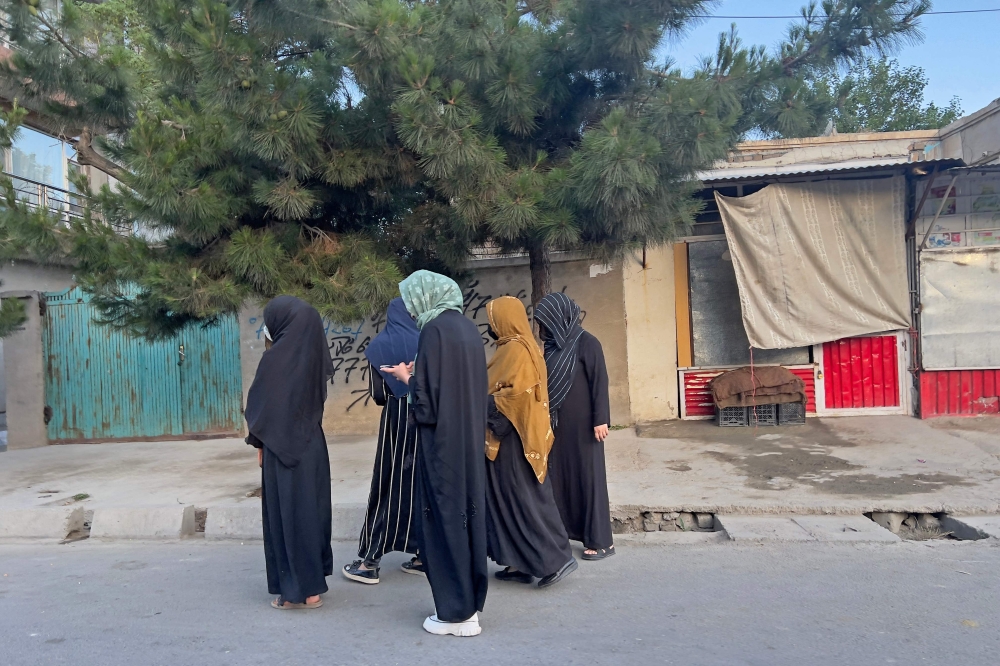 In this photo taken on June 26, 2024, an Afghan woman walks along a street at dawn in Kabul. - AFP image