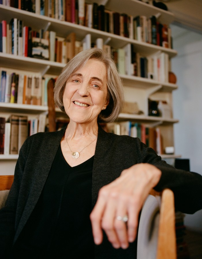 Rita Charon sat in a chair in front of a wall full of books on a shelf